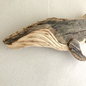 A hand carved close up of a whales head on a white background