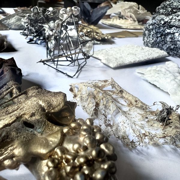Laid out urban foraged materials of various mediums in metallic colours