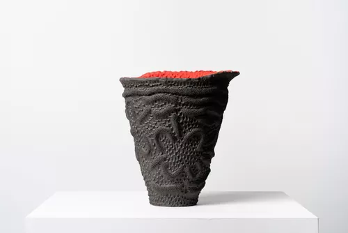 A clay vessel art piece sits on a plinth