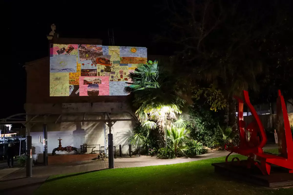 photo of collage projected on wall in forecourt after dark