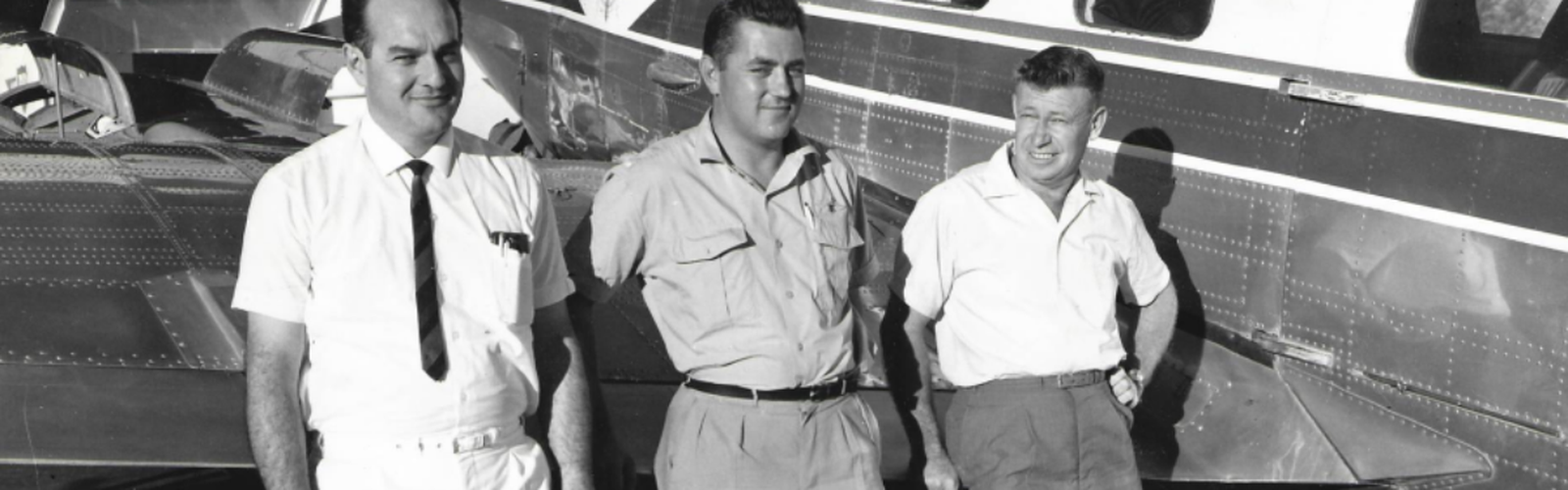 3 men are standing in front of an RFDS aircraft. Liane's father is on the right hand-side leaning against the plane. The image is in black and white.