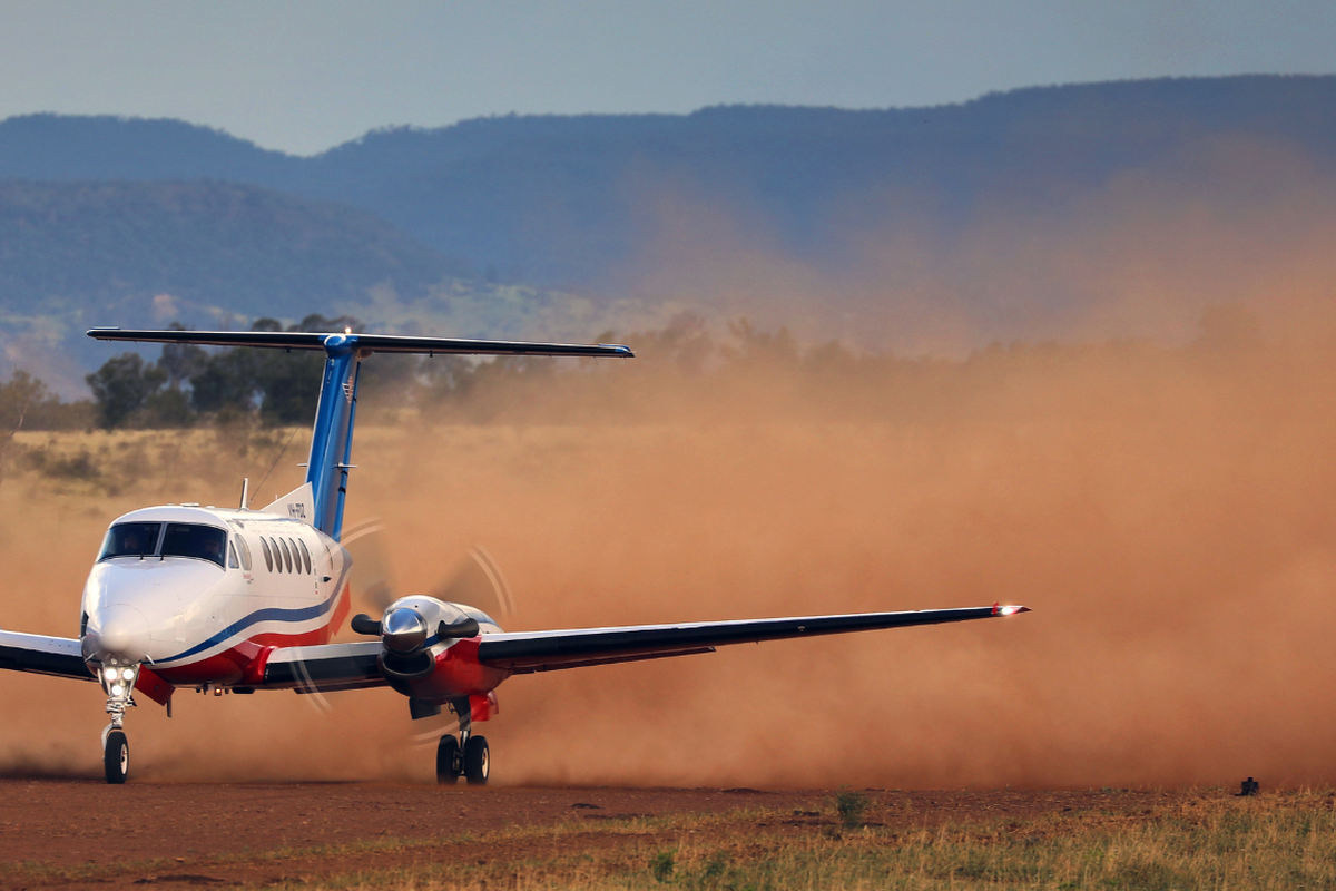 An RFDS aircraft lands on a dirt strip.
