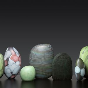 A collection of seven intricate glass sculptures positioned on a dark black surface, showcasing their different hues of green, white and red. Each piece has a different pattern texture.