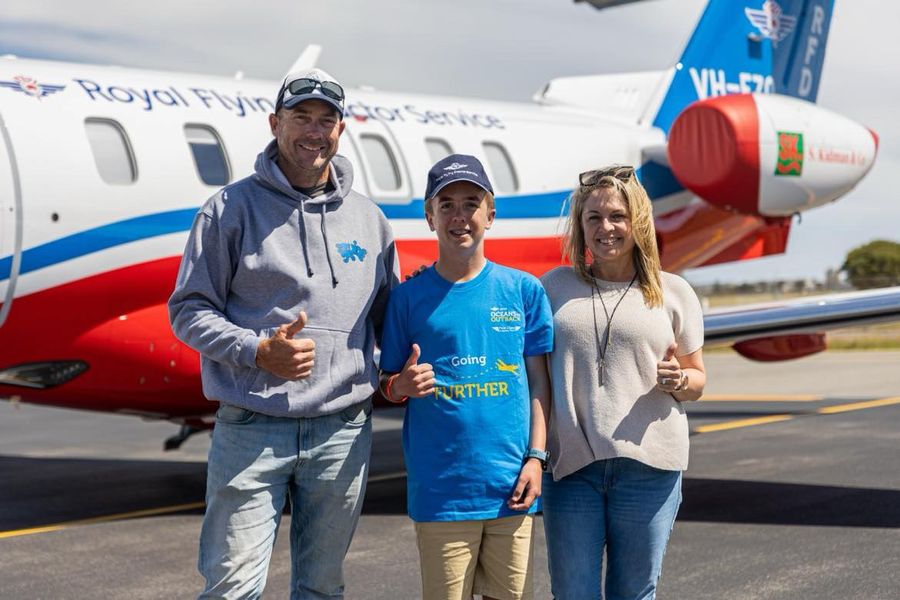 Clay pictured with his Dad, Michael and his Mum, Simone, in front of an RFDS aircraft