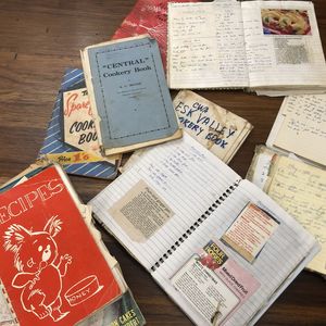 Hand written and pasted recipe books scattered across a table
