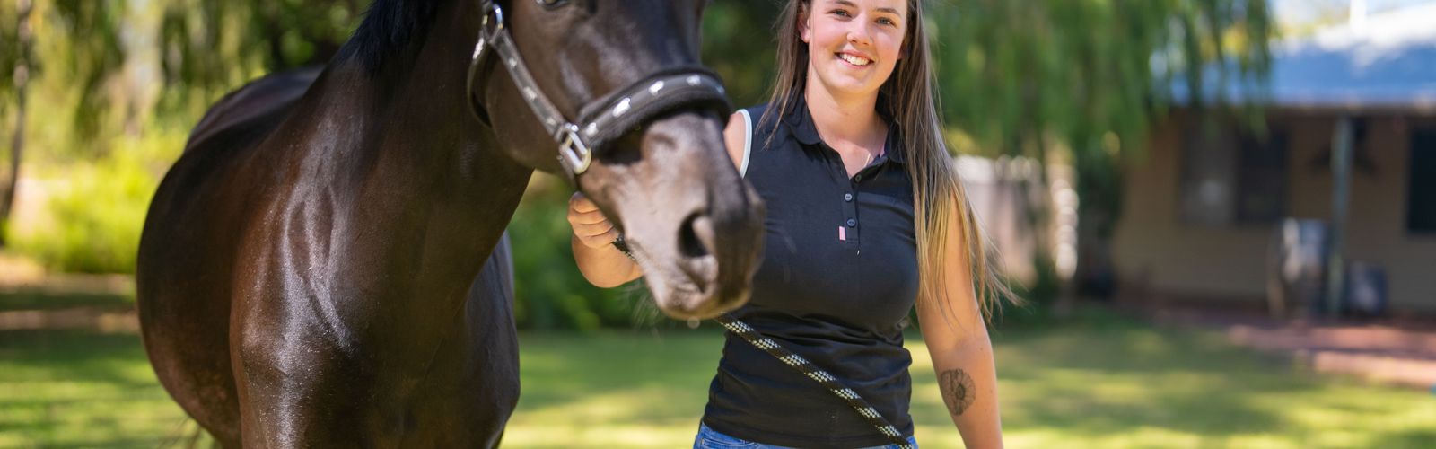 Bella smiling next to a horse