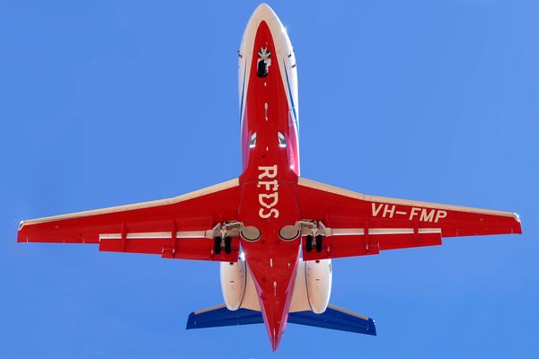 The red bottom of a jet aircraft as seen from the ground. RFDS is pained in white writing. 