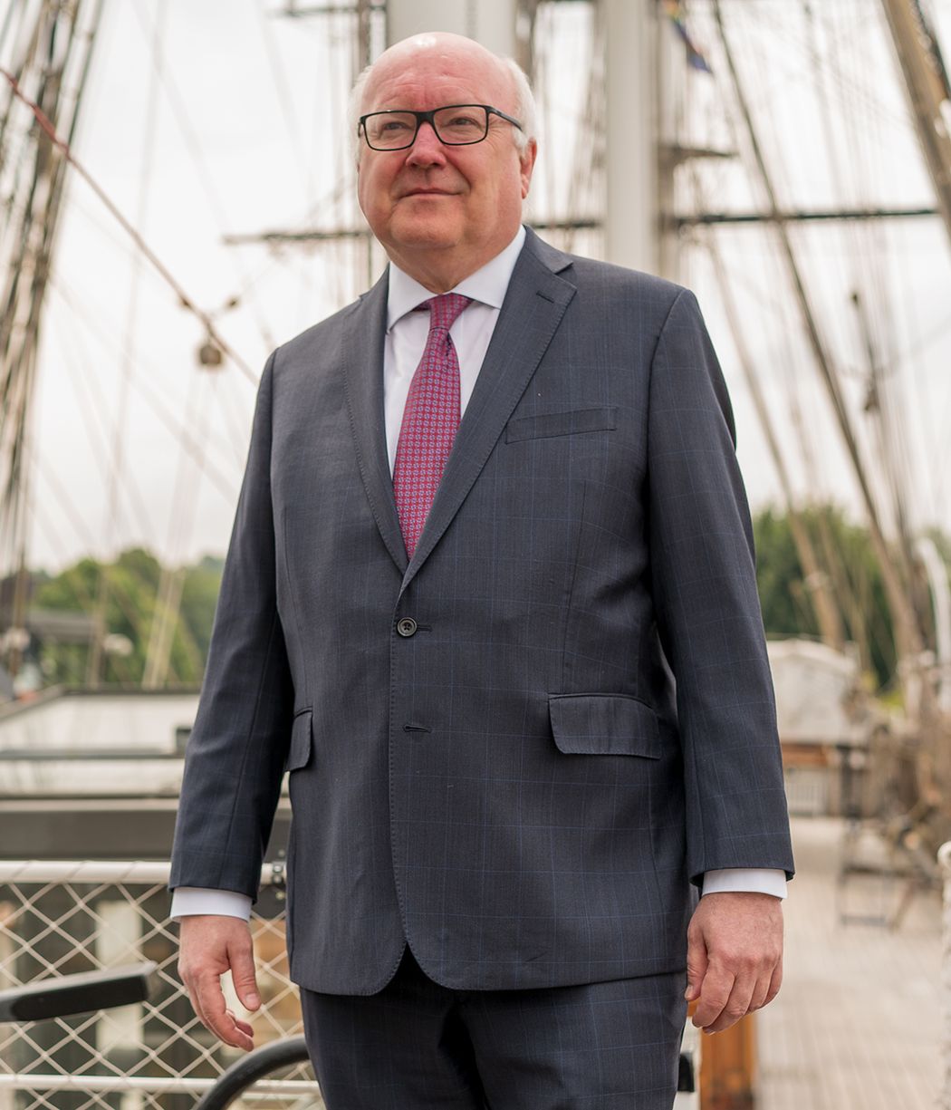 Portrait photo of George Brandis standing in front of the Cutty Sark