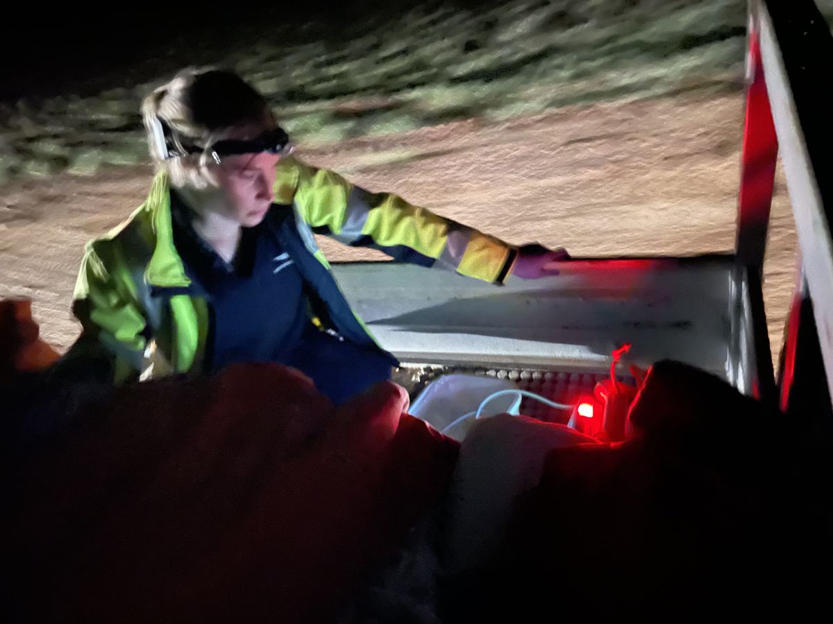 Dr Jess Martyn rides on the back of a ute, transporting Shirley to the aircraft