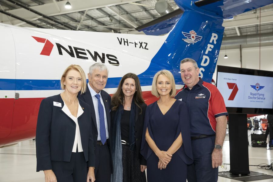 Five people smile at the camera. They are standing in front of a RFDS aircraft. 