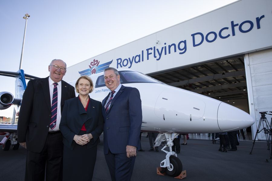 3 people in business attire stand in front of a RFDS jet aircraft