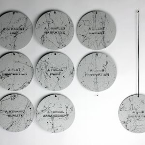 A collection of nine circular plaques, each engraved with distinct phrases, arranged together for display.