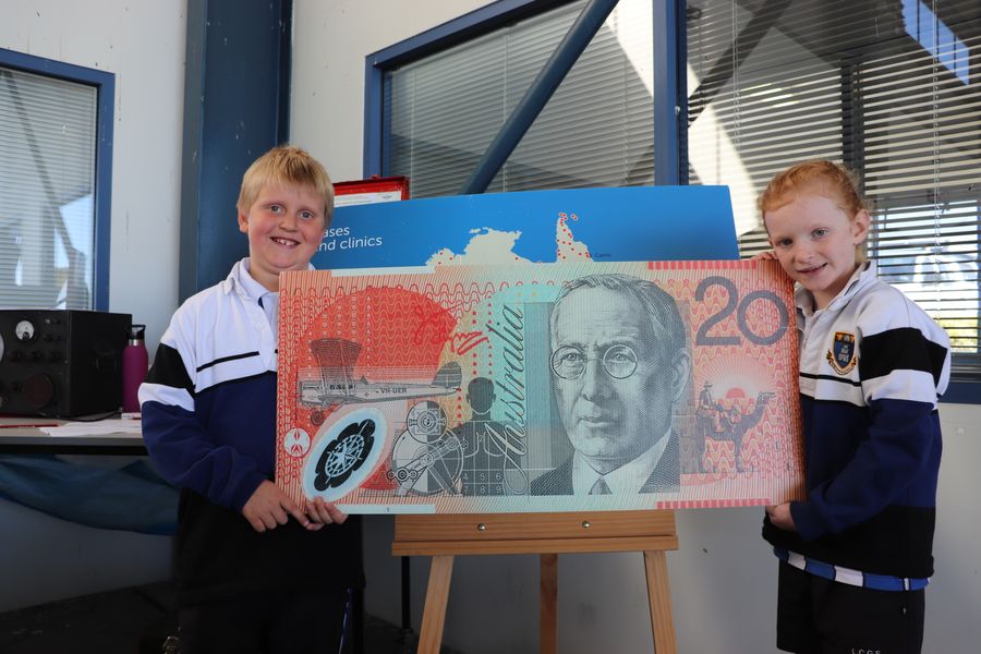 Children with 20 dollar note featuring John Flynn, RFDS founder