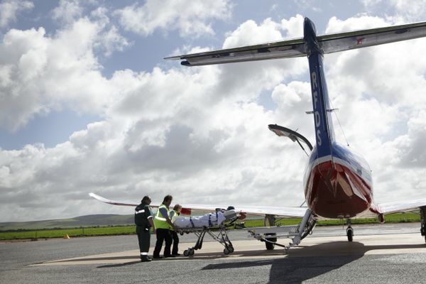 3 people holding an oversized cheque made out to the RFDS for $140,000 smile at the camera. 