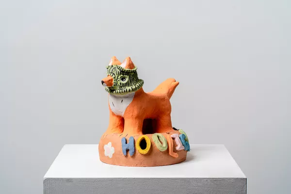 A ceramic figure of a fox wearing a balaclava with the word "hooligan" fixed to the base