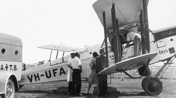 four people standing in front of a plane next to an ambulance, image is in black and white indicating it is from a long time ago