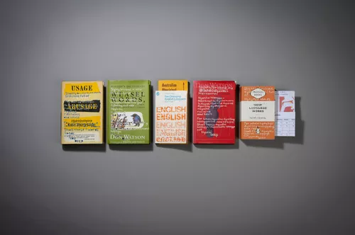 A row of books with engravings on the cover are arranged in a row on the wall