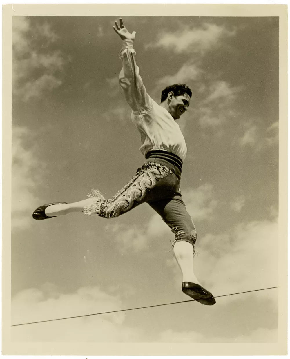 A black and white photo of a man walking a tightrope