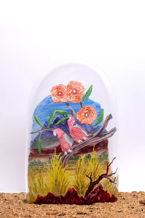 An installation shot of a painting of birds in nature on glass