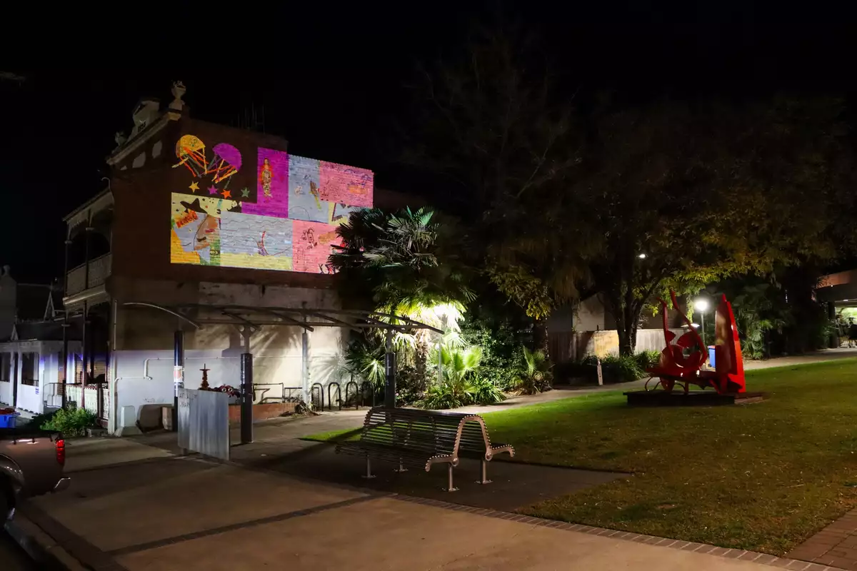 photo of collage projected on wall in forecourt after dark