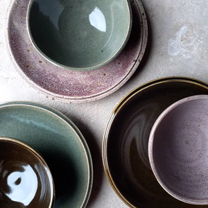 A range of stoneware plates glazed in greens and purples