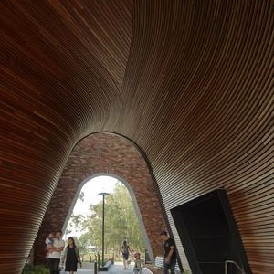 Families walking under the grand arched entrance facade of Arkadia finished with sculptural timber lengths and brick