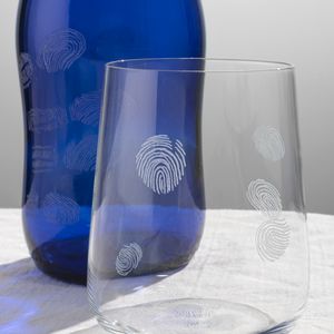 A close up image of a clear glass and blue bottle with engraved fingerprints on the surface