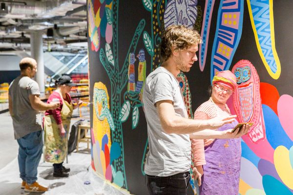 An artist from Studio A working on a detail of the wall painting, 'Bird Life Jungle Disco'