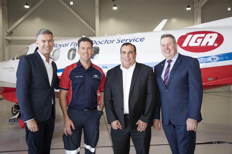 3 people smile at the camera. They are stood in front of an aircraft with RFDS logo. There is one female and two males. 