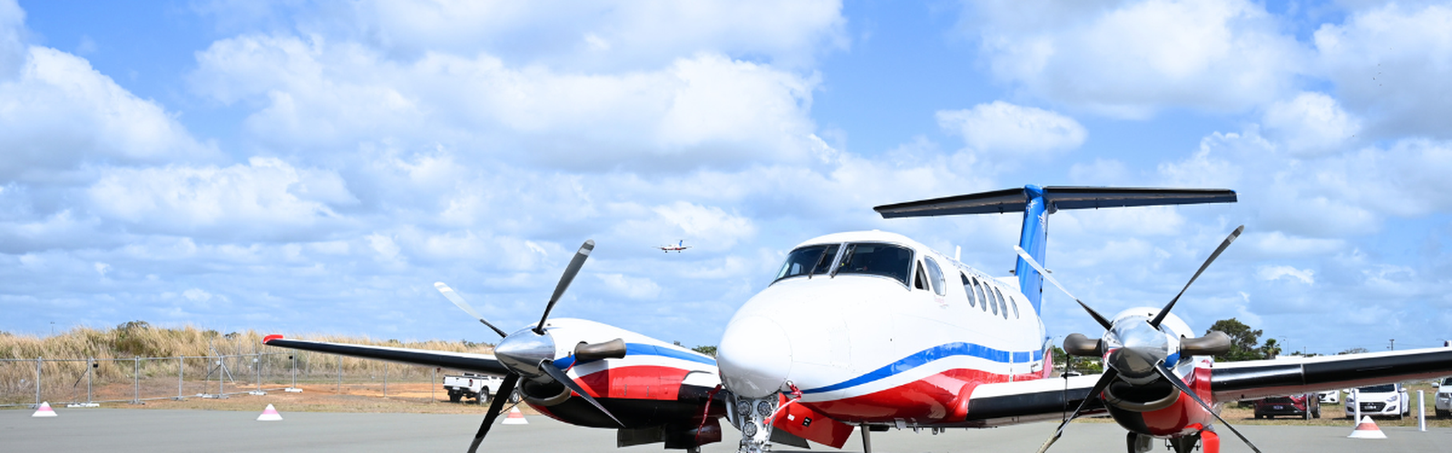 RFDS aircraft on Bundaberg airport tarmac with another RFDS aircraft in sky 