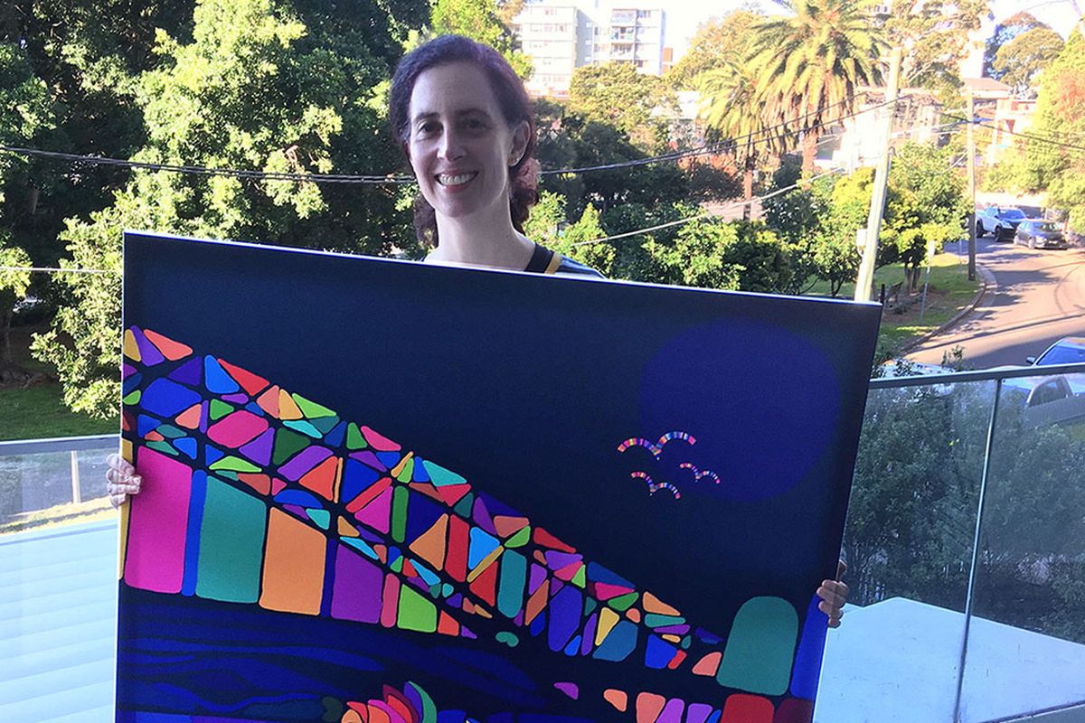 Portrait of artist Shana Danon holding a large canvas artwork of a colourful Sydney Harbour Sunset