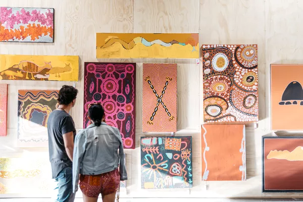 Two people look at artwork in an art market