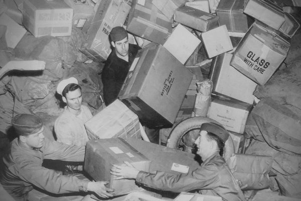 Three U.S. soldiers being almost buried by parcels at a mail depot during World War 2, circa 1944