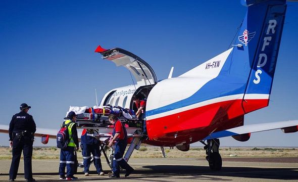 Man attending to patient next to plane