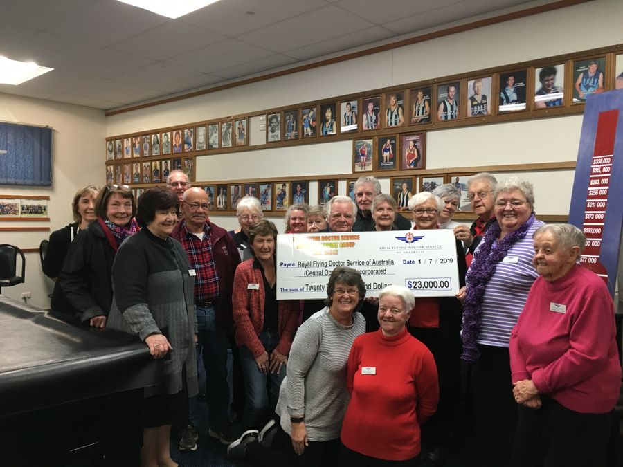 A group of people holding an oversized cheque smile at the camera. The cheque reads $23,000. 