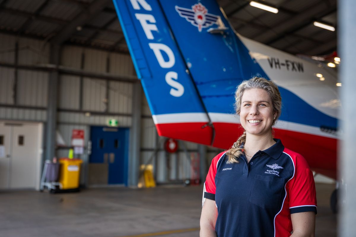Dr Sophie Ootes standing in front of an RFDS aircraft