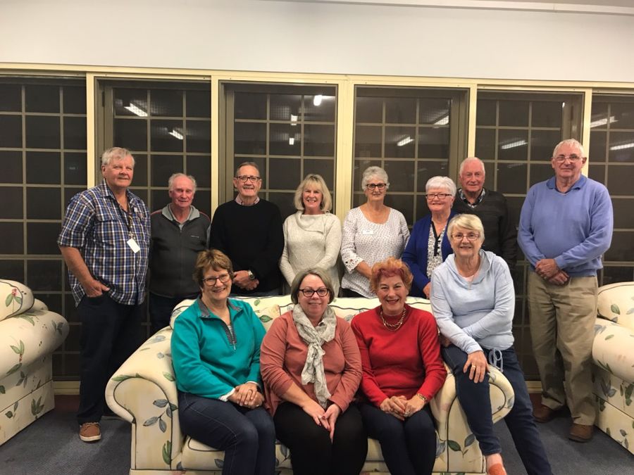 A group of people sit on a couch smiling at the camera.