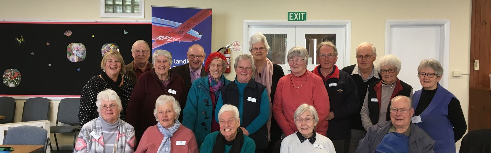 Three people are smiling at the camera and holding an oversized cheque for $40,000 made out to the RFDS. They are standing in front of a RFDS banner. 