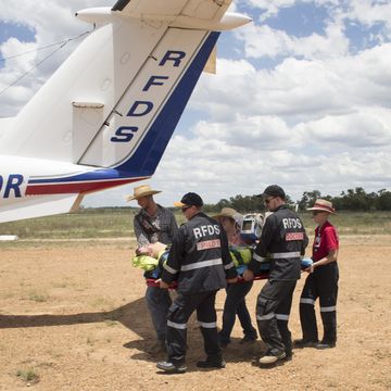 Injured stockman lays on ground with RFDS treating him