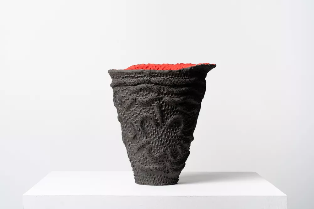 A clay vessel art piece sits on a plinth