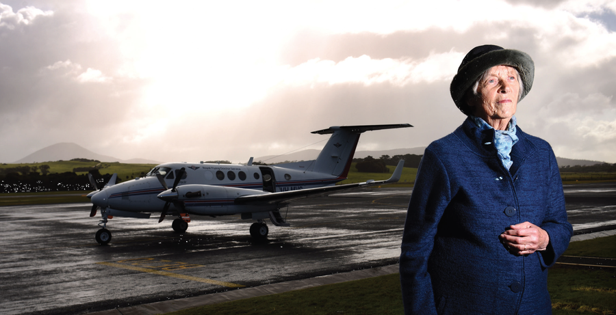 Older, dignified lady standing in foreground, RFDS plane behind her