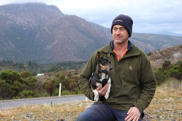 Phil and Digger wait for the RFDS Tasmania Health Hub Bus with Queenstown mountains behind.