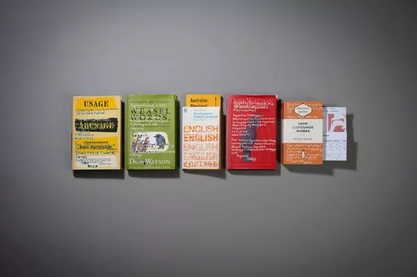 A row of books with engravings on the cover are arranged in a row on the wall