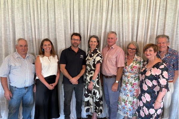 A group of people stand in front of a tan curtain including RFDS CEO Michael Ben-Meir