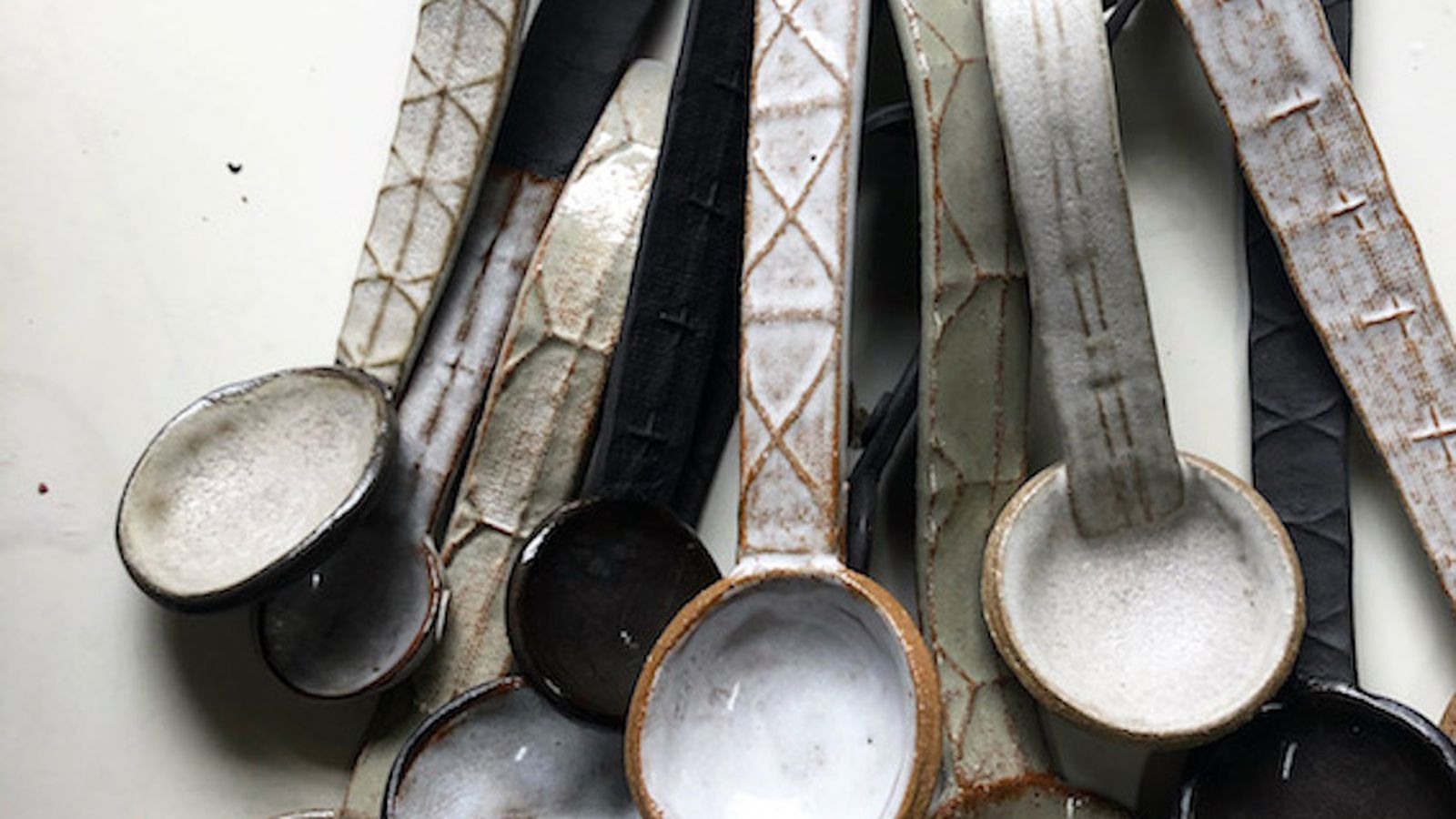 A collection of brown and cream textured ceramic spoons laid out on a flat surface.