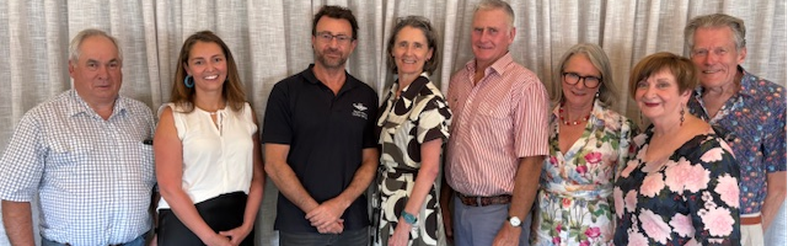 A group of people stand in front of a tan curtain including RFDS CEO Michael Ben-Meir