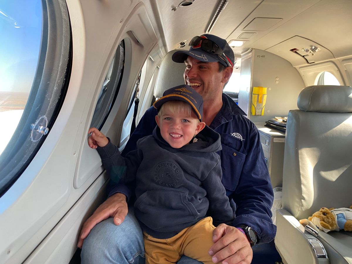 Jacob and Jack are sitting in an RFDS aircraft smiling at the camera.