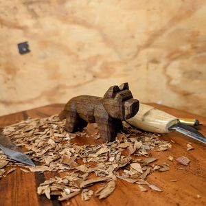 A small dog whittled out of wood and surrounded by woodshavings