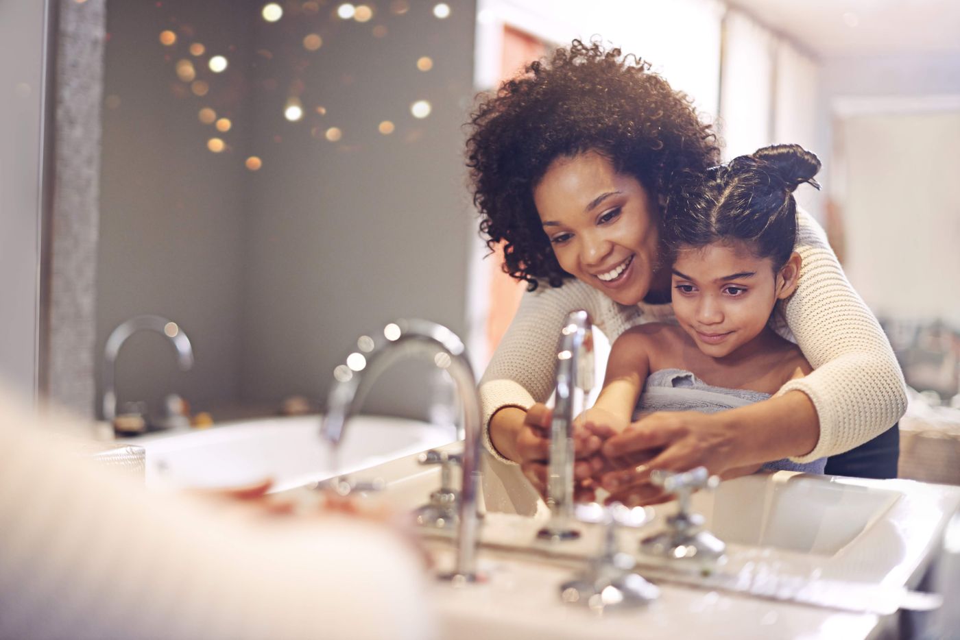 Mother and daughter using a bathroom tap together
