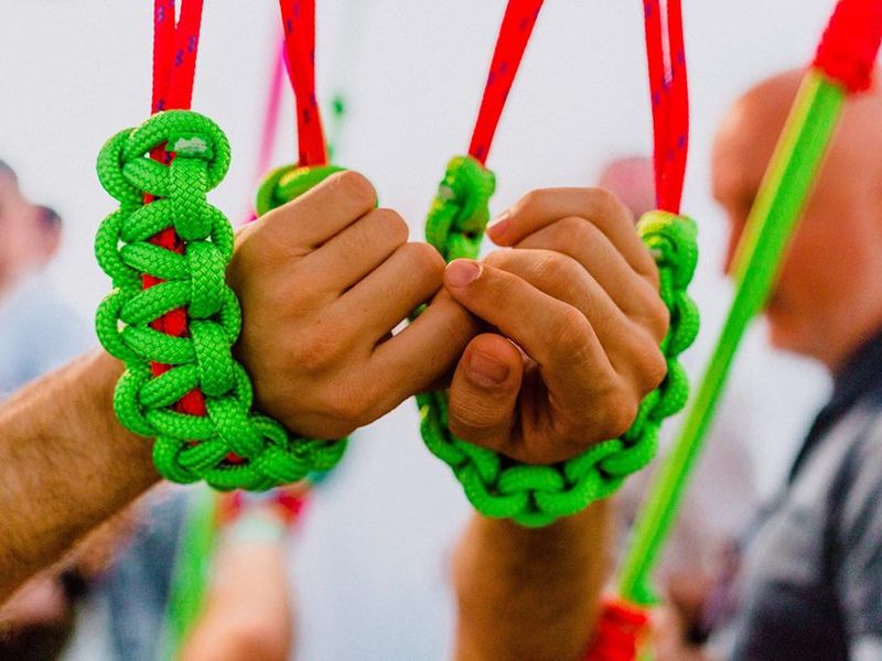 Photo close up of two hands bound in bright lime green coloured rope.